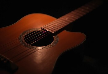 Obraz premium A close-up view of an acoustic guitar with its strings and fretboard visible in the dark