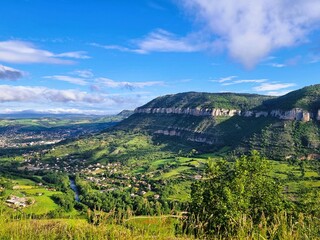 Obraz premium Vom Point de Vue du Viaduc de Millau eröffnet sich ein beeindruckender Blick auf ein französisches Tal, umgeben von einer weiten Landschaft und begleitet von Wolken am Himmel.