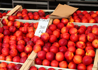 red peaches for sale at the neighborhood market stall in summer with price tag