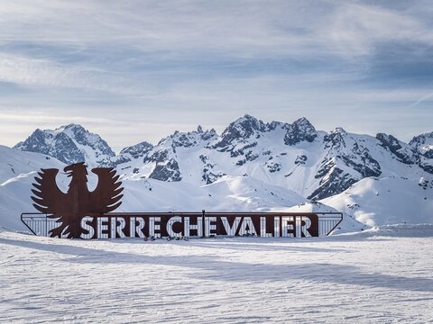Serre Chevalier sign with snowy mountain background in Briancon