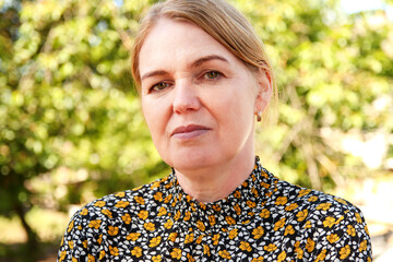A woman in her 40s with blonde hair, walking through nature. Her face reflects a sense of calm and...