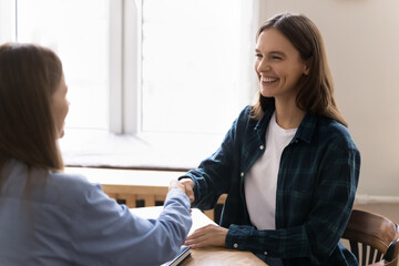 Two women colleagues shaking hands as gesture of positive outcome of formal interaction or agreement conclusion. Vacancy candidate successfully secured position, finish meeting or negotiations event