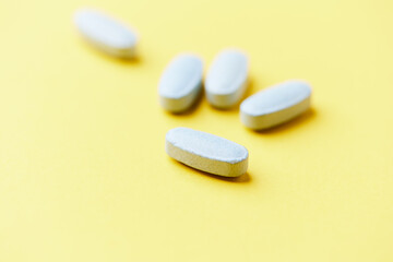 Multivitamin tablets on bright paper background. Close up. Copy space	