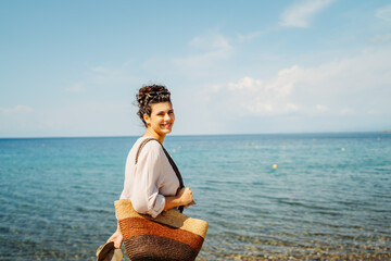 Young caucasian woman is going to the beach with straw bag	