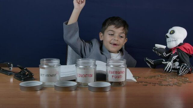 Child reading finance book, gets an idea and put coins into investment jar. Early financial education concpet. High quality 4k footage