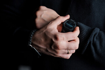 Close-Up of a Man's Hands Adjusting a Digital Sports Watch in Low Light