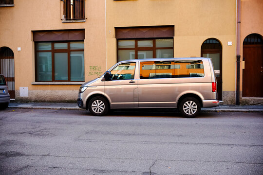 Modern silver volkswagen caravelle t6 california parked on the street in front of a residential building with a free slime graffiti on the wall