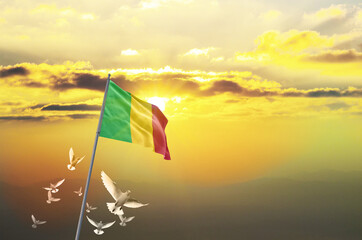Mali flag waving with flying doves against sunset or sunrise. Mali flag for Republic Day and...