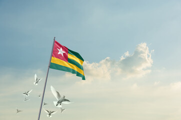 Togo flag waving with flying doves in beautiful sky. Togo flag for Republic Day and Independence Day.