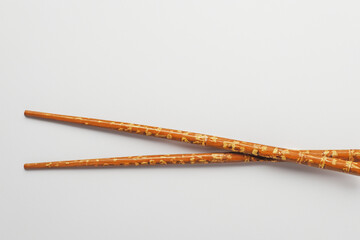 Man is demonstrating how to use chopsticks to chop meat in dark . n food concept. pair of chopsticks lying on a gray . a man lies on a wooden board with chopsticks on lifestyle a gray.