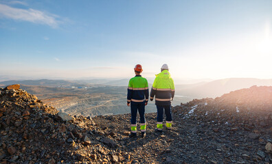 Engineers mine workers in open pit of ore, back view. Concept work process of industry quarry.