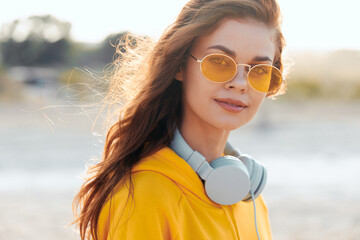 Relaxing beach day vibes woman in yellow shirt and sunglasses listening to music on headphones