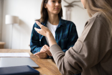 Cropped close up shot two women lead dialogue seated at workplace table, employee provide...