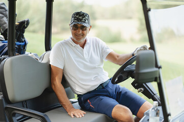 A man enjoying a round of golf while sitting in a golf cart on a sunny day at a picturesque golf...