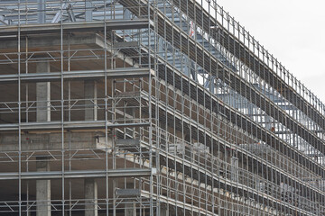 Fototapeta premium Construction of a new reinforced concrete building with metal safety scaffolding