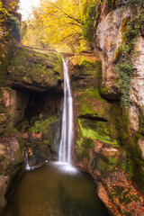 Waterfall at Moulin du Saut, an 18th century derelict mill in a forest of autumn colours on the...