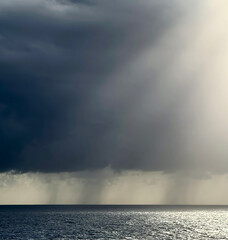 Dark cumulonimbus clouds tower over the Caribbean Sea with penetrating shafts of sunlight giving a dramatic seascape