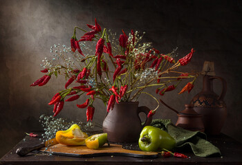 Still life with a bouquet of hot peppers and gypsophila on a dark background.