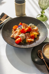 Hearty breakfast in a restaurant with prosciutto, tomatoes and cream cheese