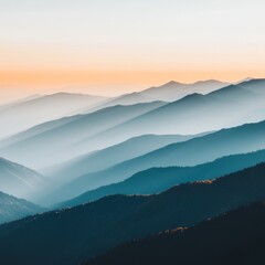 Fototapeta premium Misty mountain range at sunset with layers of blue and orange hues.
