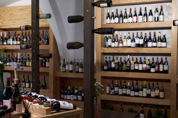 Obraz premium Huge vertical wine racks with different types of wine in center of wine cellar with wooden cabins to store wine