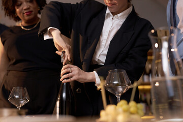 Low angle shot of unrecognizable female sommelier opening wine bottle with corkscrew before...
