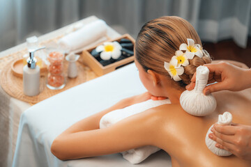 Hot herbal ball spa massage body treatment, masseur gently compresses herb bag on woman body....