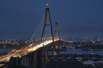 Obraz premium stunning view of suspension bridge at night, illuminated by city lights and traffic. scene captures vibrant energy of urban life