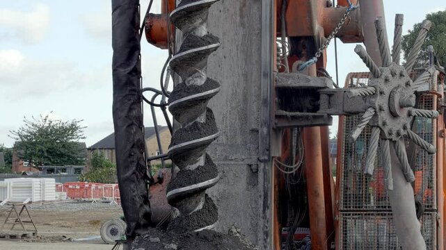 Construction drill piling rig auger operates on site in urban area, demonstrating deep foundation techniques for buildings
