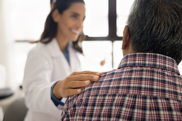 Close up kind female therapist touch shoulder of senior male patient during conversation at his visit in clinic, discuss successful therapy, effective treatment, encouraging, giving support. Eldercare