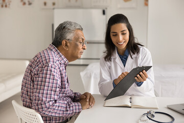 Smiling female doctor wear white lab coat consulting older male patient about treatment plan,...
