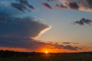 Obraz premium Colorful nature background: the sun at sunset sits on the horizon line