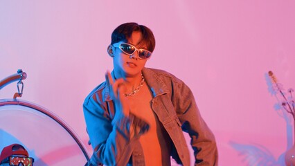 Close up of asian street dancer moving to pop music with neon light while diverse friend sitting and support performance. Professional performer practicing dancing step to beat at studio. Regalement.