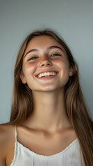 Fototapeta premium Portrait of smiling Caucasian young adult girl with engaging and joyful expression on clean backdrop