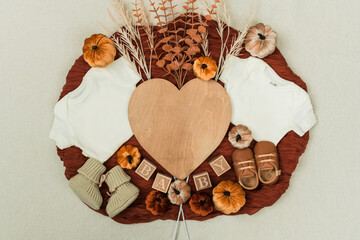 A cozy flat lay featuring a baby bodysuit, pumpkins, leaves, and rustic fall decor. Perfect for...