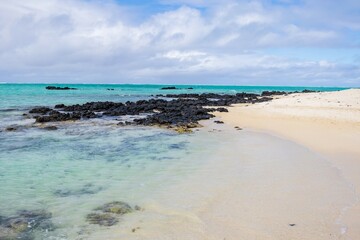 Serene Beachscape with Clear Turquoise Water and Black Volcanic Rocks in Ile aux Cerfs Mauritius