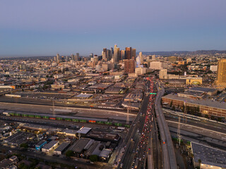 Fototapeta premium Aerial view of early commute to downtown Los Angeles before sunrise, with traffic queuing up. Los Angeles skyline in the background. 