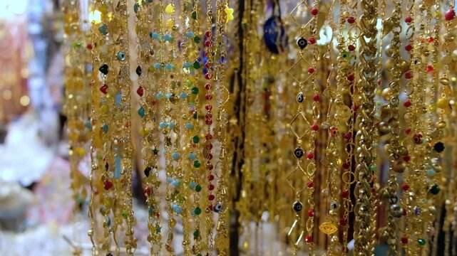 Row of golden jewelry bracelets hanging on a display and swinging on wind at traditional middle eastern bazaar