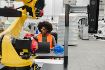 Robotics engineer programming automated machines in factory