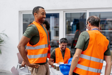 Multiracial engineers wearing safety vest having a break in factory