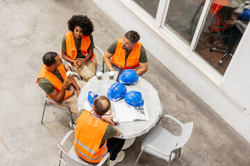 Multiracial engineers team having a coffee break during a meeting in a factory patio