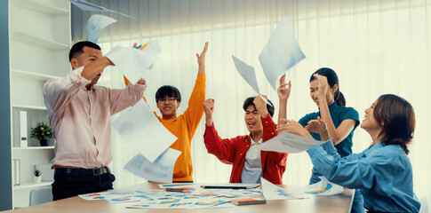 Excited and happy startup company employee celebrate and throw paper in the air after make...