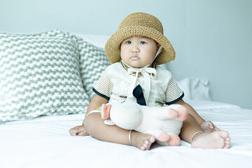 Adorable child sitting laughing on bed playing with dolls in bedroom,Cute girl playing with dolls on the bed,