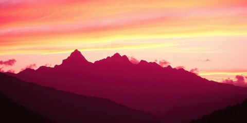 Obraz premium A majestic mountain range silhouetted against a vibrant sunset sky, showcasing the beauty of nature's artistry.