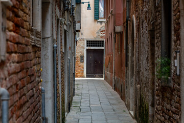 a view into a deserted narrow alley in Venice with dilapidated walls