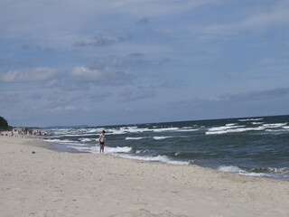 Beach day with waves and people on the seashore under a blue sky
