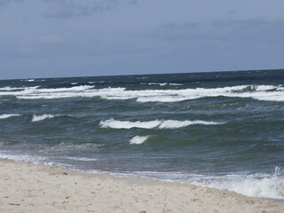 Beach with waves and sand under blue sky on sea coast