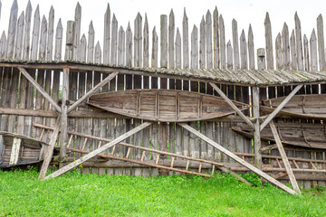 An old wooden boat is hanging on a wooden wall for storage
