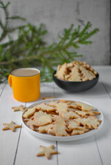 Two plates of homemade Christmas cookies and an orange large cup of cocoa. A spruce branch in the background, vertical position.