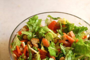 Bowl of lettuce, tomato, carrot, chickpea, cheese and toast salad. Selective focus.